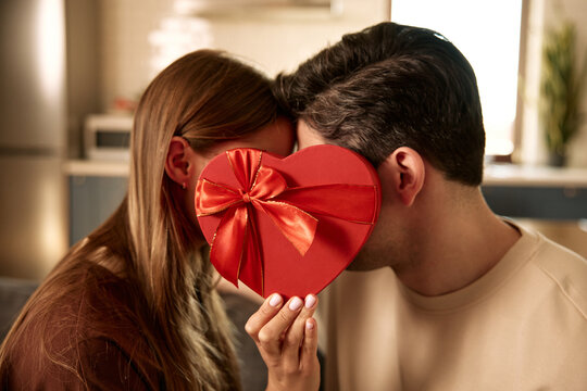 Couple hiding behind heart shaped gift box on Valentine's Day