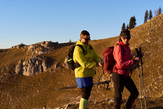 Hikers preparing for a sunset trek in the mountains with vibrant colors and rocky terrain