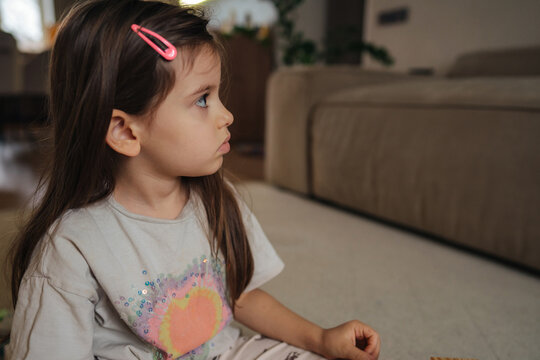 white girl gazing sideways indoors, serene caucasian female sitting on ground with calm expression - Powered by Adobe