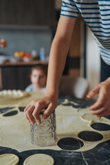 child observes parent shaping cookies, warm kitchen glows as family crafts sweet treats together