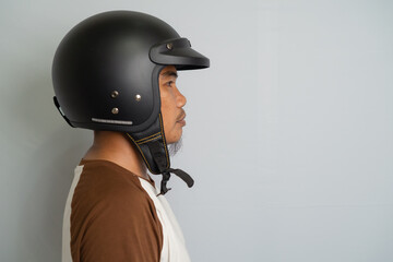 Man Wearing Black Open Face Motorcycle Helmet Side Profile On Gray Background Neutral Tones Casual Outfit