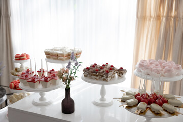 An elegant dessert table with a variety of desserts. The light interior, soft pastel colors and floral decor create a festive atmosphere.