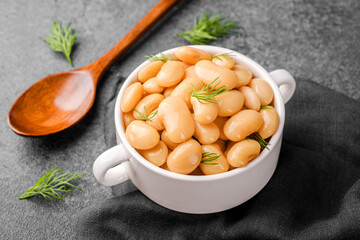 white beans in tomato sauce with herbs in white bowl on gray background for clean eating, comfort food or healthy lunch concept