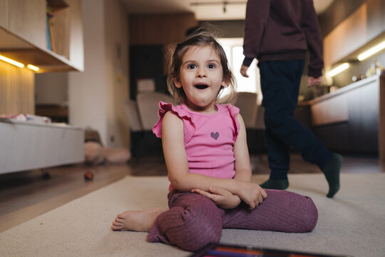 enthusiastic girl relaxing on kitchen floor with parent silhouette in warm evening atmosphere