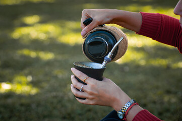 Mujer joven sirviendo mate en el parque, momento de tranquilidad al aire libre. © Daniel