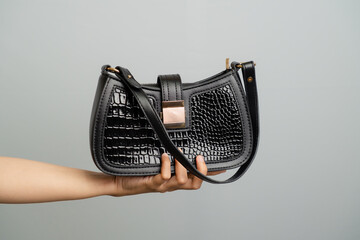 Black Patent Croc Embossed Shoulder Bag Held By Hand On Plain Background