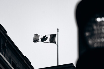Canadian flag waving on a building rooftop against a bright sky, Montreal