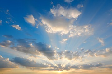 Fototapeta premium Sun rays shining through the clouds in a blue sky creating a beautiful atmospheric effect