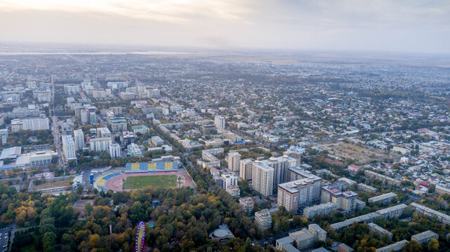 Bishkek residential districts and large Soviet apartment blocks sprawl toward industrial smokestacks Chuy Valley, Kyrgyzstan. Drone aerial photo

