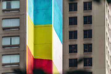 Colorful geometric mural painted on the facade of a tall building near UQAM, featuring bold vertical blocks of blue, red, yellow, and turquoise