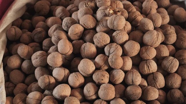 Close-up of ripe, unshelled walnuts in canvas bag at local organic market. Unshelled raw nuts. Top view. Healthy, micronutrient-rich, superfood. Vegan-friendly. Small business, wholesale food trade