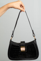 Hand Holding Small Black Sequined Shoulder Bag With Gold Clasp Accent Studio Shot