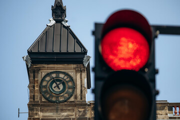 Montreal City Hall clock tower with Roman numerals and red traffic light in foreground