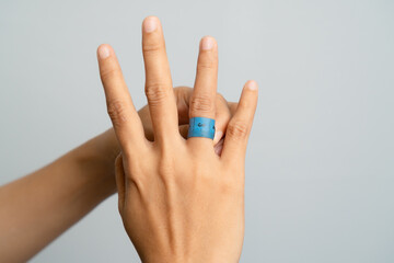 Hand Wearing Blue Textured Ring Showing Three Fingers Against Gray Background Studio Shot