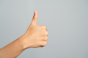 Hand Showing Thumbs Up Gesture With Light Skin Tone Against A Light Gray Studio Background
