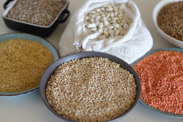 Bowls and bags full of various healthy grains and legumes. Selective focus.