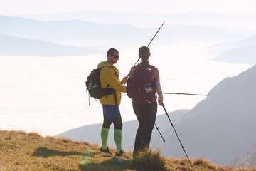 Hiking couple enjoying a stunning view above the clouds on a sunny day