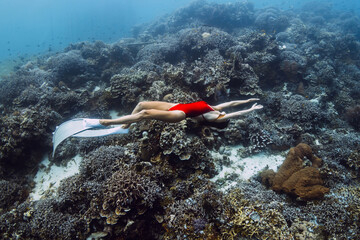Freediver woman swims in underwater with living corals. Free diving in Raja Ampat