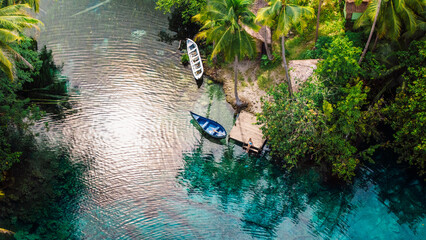 Woman sitting on pier near blue lake with transparent water in Indonesia. Aerial view