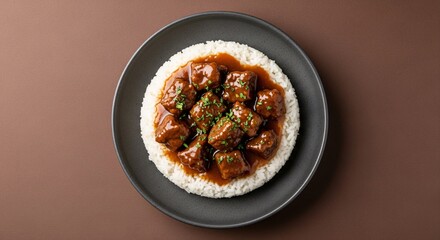 Delicious beef tips with rice recipe served on a black plate from above view