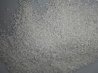 Raw white sago pearls (tapioca balls) displayed as a texture or in a heap, representing a starchy ingredient for traditional Asian puddings and desserts.