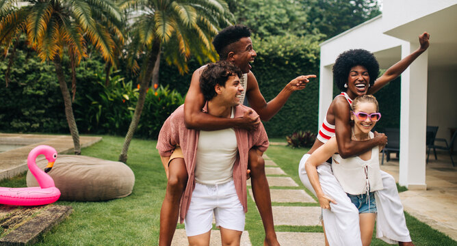 Joyful friends playfully piggybacking outdoors