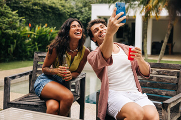 Friends take selfie at outdoor poolside gathering