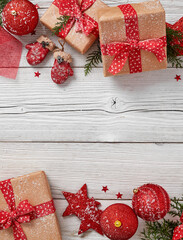 Festive Christmas flat lay composition featuring gifts, ornaments, and fir branches on a white wooden table