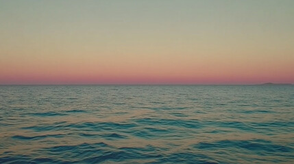Vast ocean stretching to the horizon under a gentle gradient of twilight sky, reflecting tranquil water movement and a distant landmass