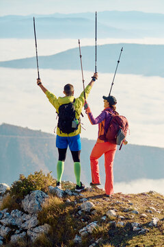 Couple celebrating a successful hike on a mountain peak with scenic views during early morning