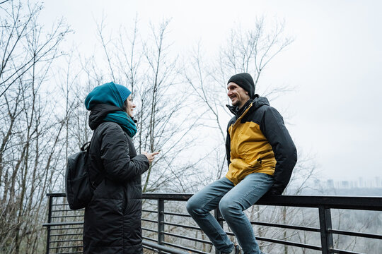 recreational hikers exchange friendly chatter in foggy forest setting, casual hikers in vibrant clothing engage in cheerful conversation surrounded by misty trees and overcast sky