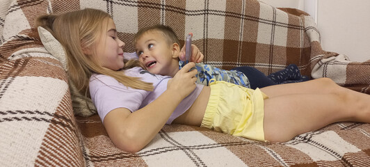 Girl and toddler playing together on couch at home