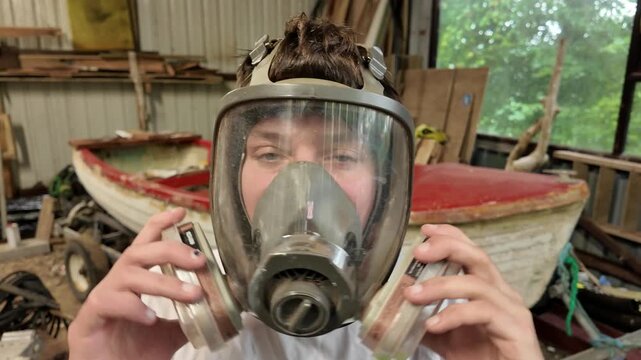 Worker puts on facemask respirator for fiberglass boat work