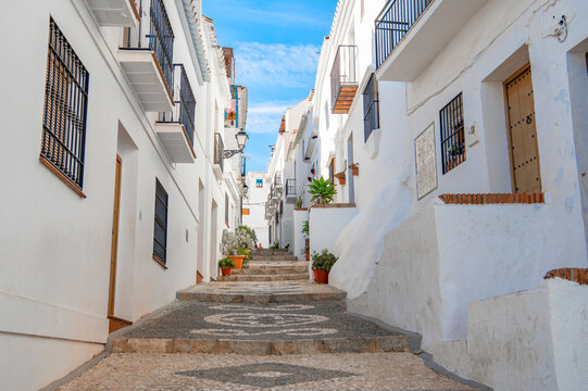 Narrow street of Frigiliana, Malaga, Andalusia, Spain. Cozy Andalusian town with white houses, flowers, colorful doors and windows. White Village. Travel concept