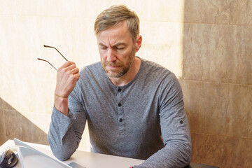 Focused middle-aged man with a pensive expression working at his desk. Stress and burnout concept