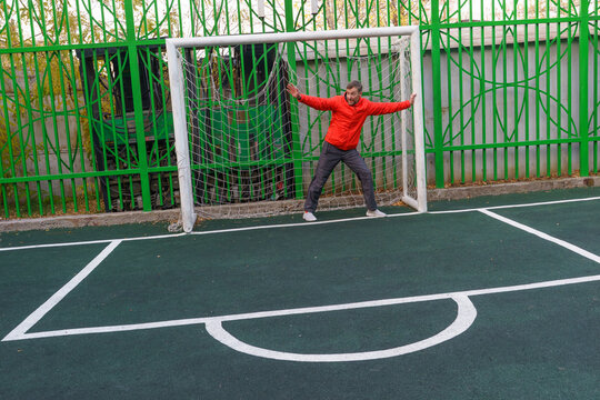 Active middle-aged man defending a soccer goal. Goalkeeper training on an outdoor sports field