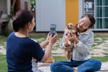 Senior Asian mother using smartphone to take photo of daughter representing active aging and modern family bonding