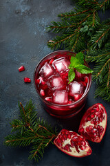 Refreshing pomegranate drink served with mint and ice on a dark background in a cozy setting