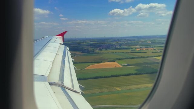 A view from the airplane window of the wing and fields as the plane lands. High quality 4k footage