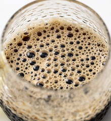 A glass of coffee with bubbles in it
