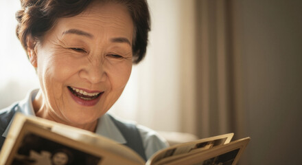 Close up of a happy senior woman laughing over a photo album. Elderly Asian grandmother reminiscing about fond memories at home