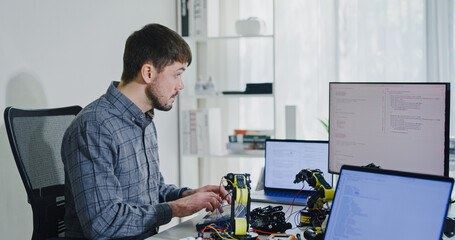 Young adult male freelance developer typing write prompt AI bot app program nomad terminal with coding at office. Artificial intelligence dashboard, robotics, user interface, machine learning concept.