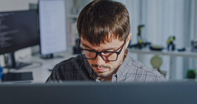 Closeup young adult male freelance developer typing write prompt AI bot app program nomad terminal with coding at office. Artificial intelligence dashboard, robotics, user interface, machine learning.