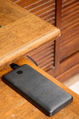 Indoor. power bank placed on the corner of a wooden desk