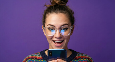 Excited young woman with glasses looking at smartphone screen with surprised expression on purple background