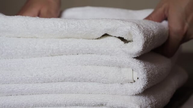 Close-up of hands placing white bath towels on the bed sheet. Concept of room cleaning service. High quality 4k footage