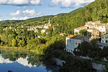 Densely packed hillside village in Sisteron, France, with stone and stucco buildings featuring terracotta tiled roofs.