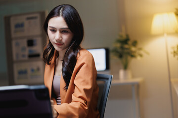 Asian businesswoman concentrating on laptop late in office