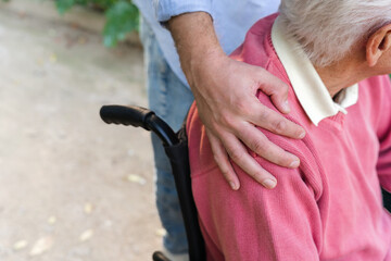 Close-up of caregiver hand on senior man’s shoulder showing support