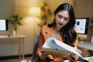 Asian businesswoman analyzing documents working late in office